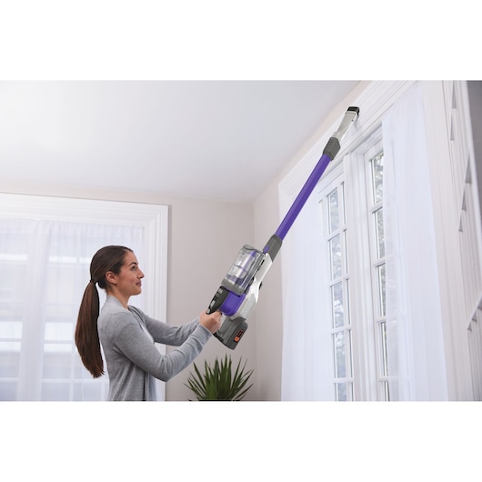 BLACKDECKER BHFEV362DP stick vacuum with purple extension cleaning window trim indoors.