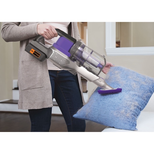 BLACKDECKER BHFEV362DP cordless vacuum cleaning pet hair from blue pillow in living room.