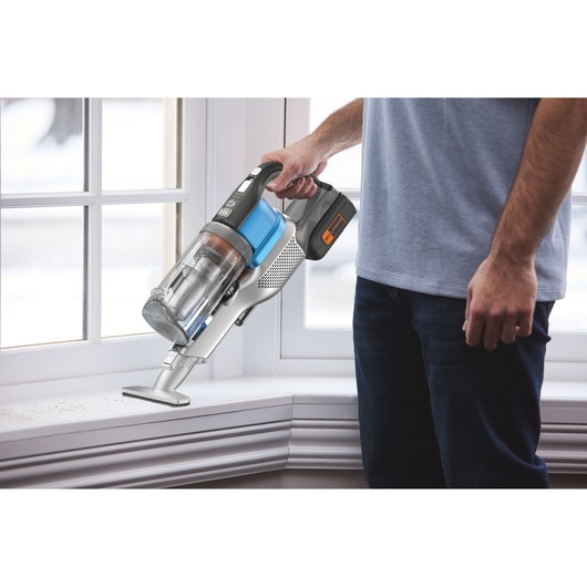 BLACKDECKER BHFEV362D cordless handheld vacuum in use cleaning a white windowsill.