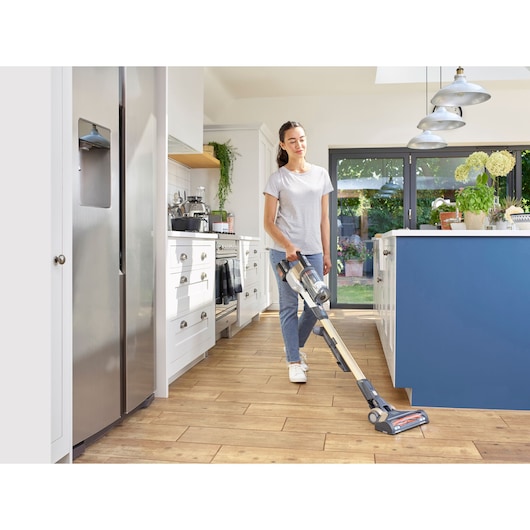 BLACKDECKER BHFEV36B2D cordless stick vacuum cleaner used on kitchen wooden floor.