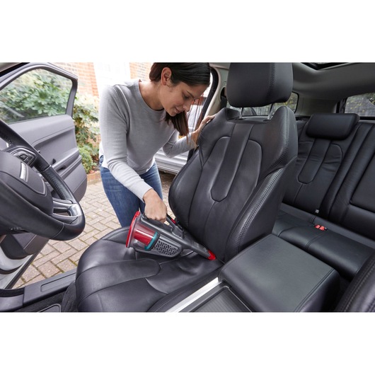 BLACKDECKER BHHV315J handheld vacuum cleaning black car seat in interior setting.