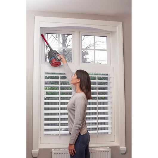 BLACKDECKER BHHV315J handheld vacuum cleaning window frame, indoor setting, side view.