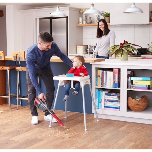 BLACKDECKER BHHV315J handheld vacuum cleaning crumbs on kitchen floor near high chair.