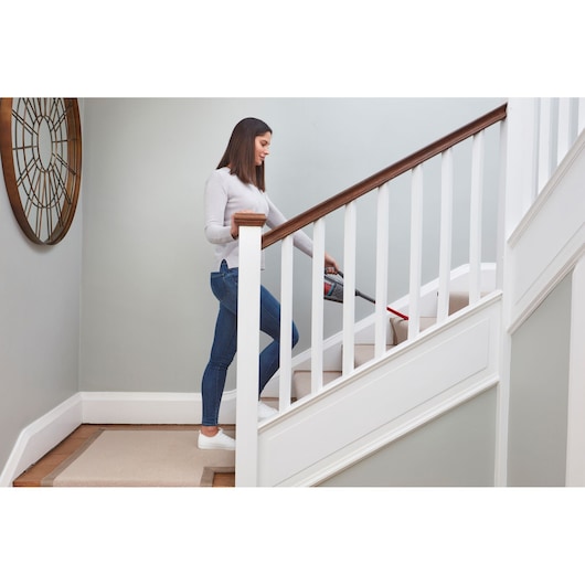 Photo of BLACKDECKER BHHV315J handheld vacuum cleaning carpeted stairs in a modern home setting.