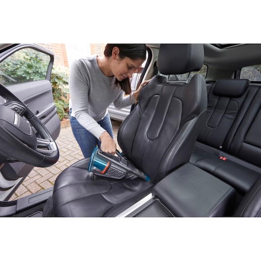 BLACKDECKER BHHV320J handheld vacuum cleaning black car seat upholstery.