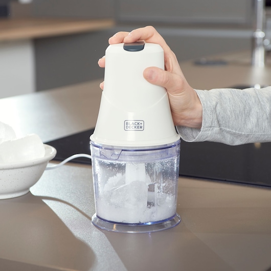 BLACK+DECKER BXCH260E ice crusher blender in use on kitchen counter, hand pressing top.