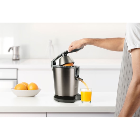 Photo of BLACKDECKER BXCJ350E citrus juicer dispensing orange juice into a glass on a kitchen counter.