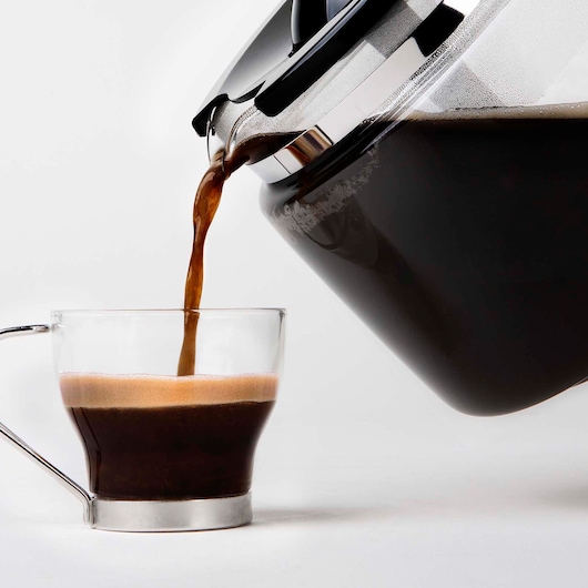 BLACKDECKER BXCO1000E coffee maker pouring hot coffee into glass cup, side angle, white background