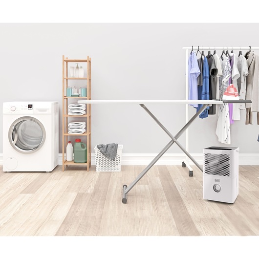 BLACKDECKER BXDH12E dehumidifier front angle in laundry room with washing machine, shelf, and hanging clothes.