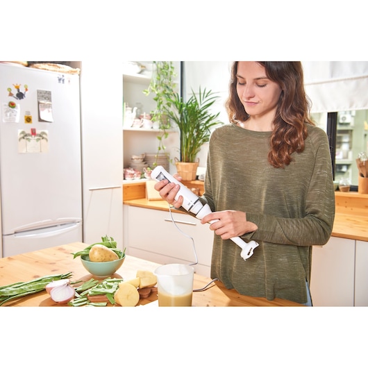 BLACKDECKER BXHB500E hand blender in use in a kitchen with vegetables and a bowl on the countertop.