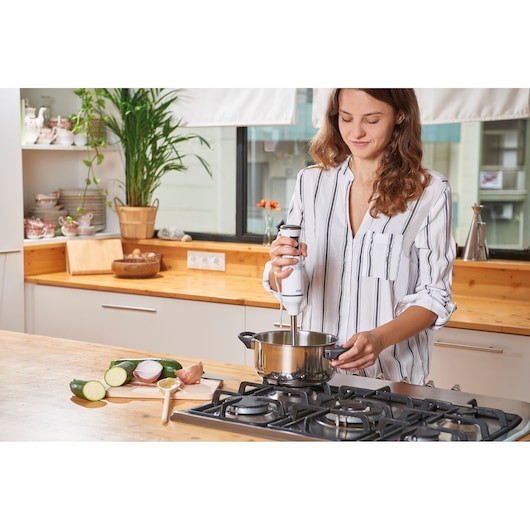 BLACKDECKER BXHBA600E hand blender used in a kitchen to blend ingredients in a pot.