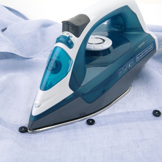 BLACKDECKER BXIR2200E steam iron, blue and white, close-up angle pressing a light blue shirt.