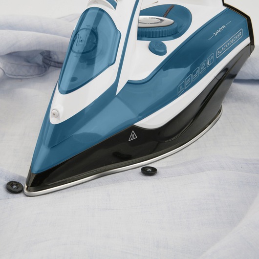 Photo of BLACK+DECKER BXIR2400E steam iron with blue and white body on a light shirt.