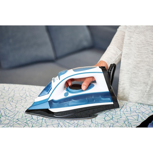 BLACKDECKER BXIR2400E steam iron in blue and white held by hand on ironing board.