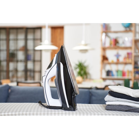 BLACKDECKER BXIR2800E steam iron on table with folded clothes, side view, in a home setting