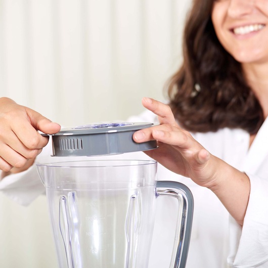 BLACKDECKER BXJB500E blender with clear jar and gray lid, close-up of hands assembling the blender.