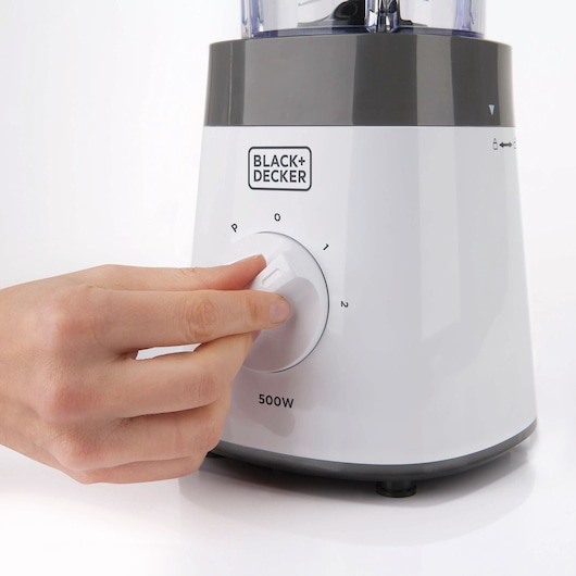 Photo of BLACK+DECKER BXJB500E blender base, white and gray, close-up of hand turning control dial, 500W power.