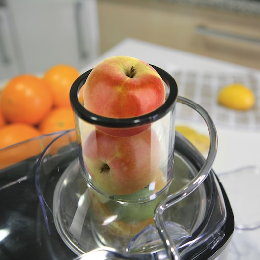 BLACKDECKER BXJE600E juicer close-up with whole apples in feed chute, kitchen background.