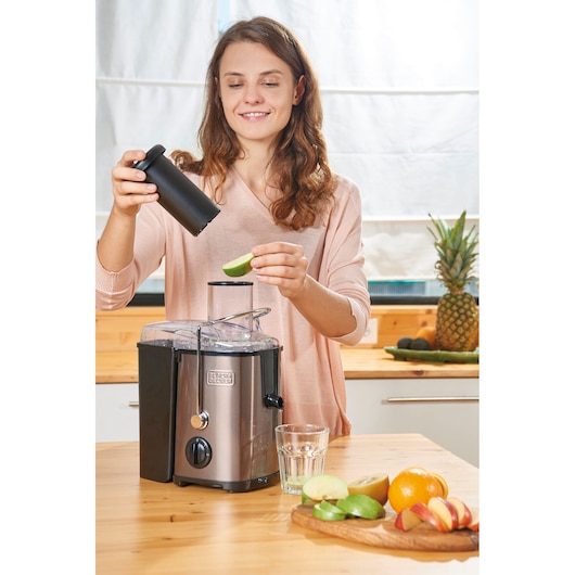 BLACKDECKER BXJE600E juicer on kitchen counter with fruit and glass, person adding apple slice.