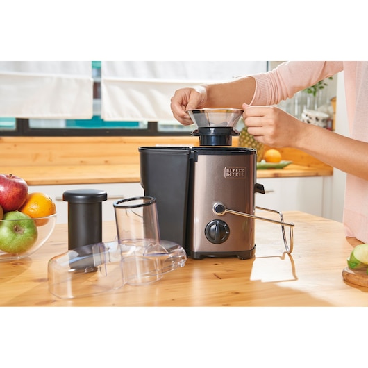 BLACKDECKER BXJE600E juicer with accessories on kitchen table, stainless steel finish, fruit bowl nearby.