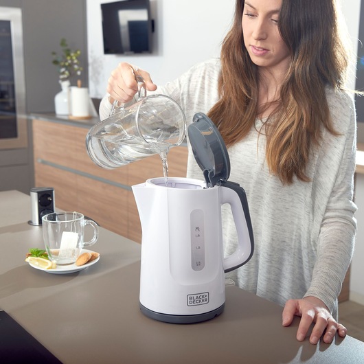 Photo of BLACK+DECKER BXKE2200E white electric kettle being filled with water in a modern kitchen.