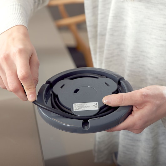 Close-up photo of a person holding the underside of a BLACK+DECKER BXKE2200E kettle base with cord storage.