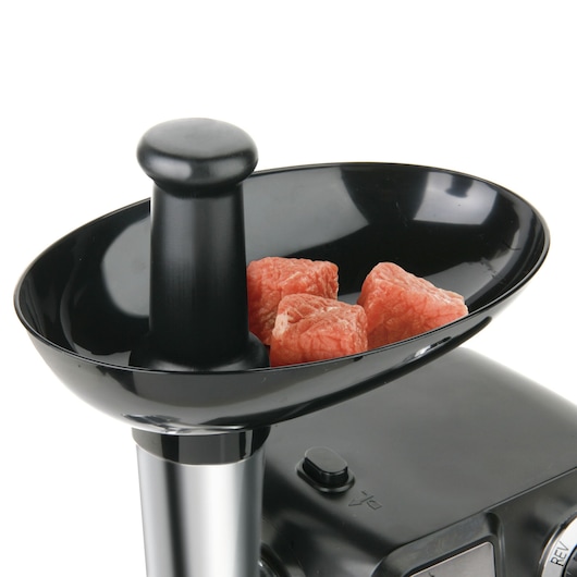BLACKDECKER BXMM1000E meat grinder tray with pusher and raw meat cubes, close-up on white background.