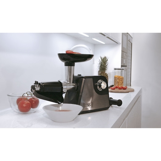 BLACKDECKER BXMMA1000E food grinder on kitchen counter making tomato sauce, bowl and tomatoes visible.