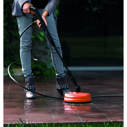 BLACKDECKER BXPW1500PE pressure washer cleaning patio tiles with orange surface cleaner attachment.