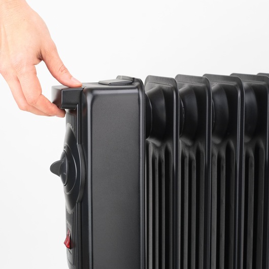 BLACKDECKER BXRA1500E oil-filled radiator side view, hand adjusting top control knob, black finish.