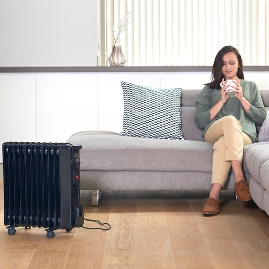 BLACKDECKER BXRA2000E black radiator heater on wheels in living room near sofa.