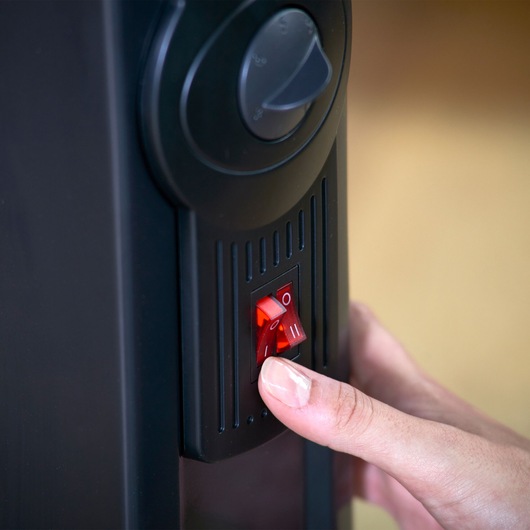 Close-up of BLACKDECKER BXRA2000E heater switch being turned on by hand.