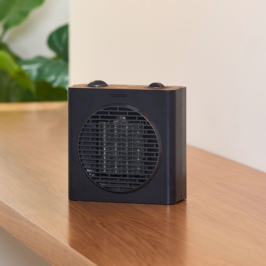 BLACKDECKER BXSH1500E black compact space heater on wooden surface, front angle.