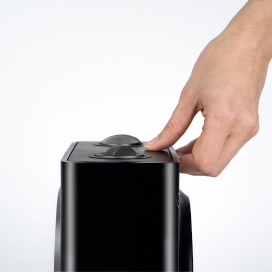 BLACKDECKER BXSH1500E heater close-up with a hand adjusting the top control dial, white background.