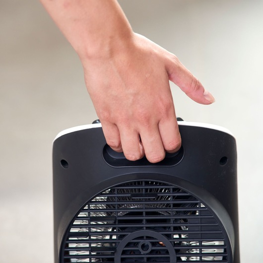BLACKDECKER BXSH2000E portable heater front view, hand holding top handle.