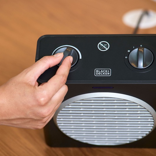 BLACK+DECKER BXSH2003E portable heater with control knobs, close-up on wooden surface.