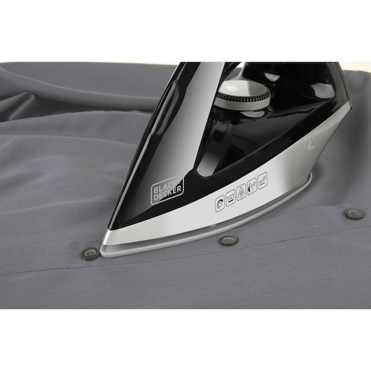 Photo of BLACKDECKER BXSS2200E steam iron soleplate in black and silver on grey fabric, close-up angle.