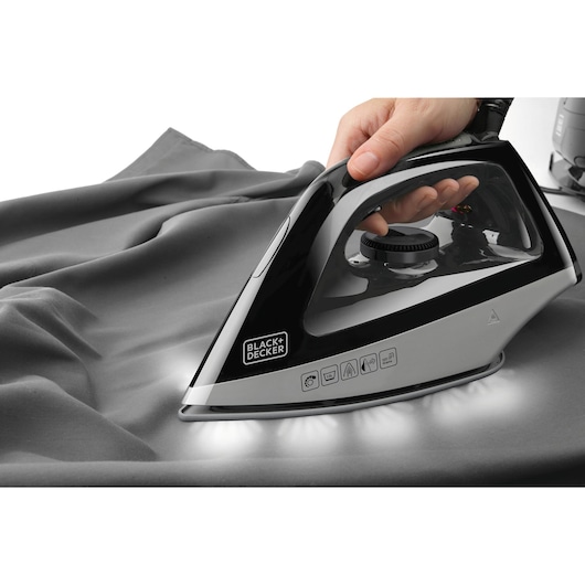 BLACKDECKER BXSS2200E steam iron in use on gray fabric, close-up side angle.