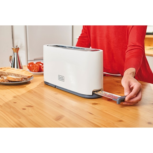 Photo of BLACKDECKER BXTO1001E toaster with crumb tray being removed on a kitchen table near sliced bread.