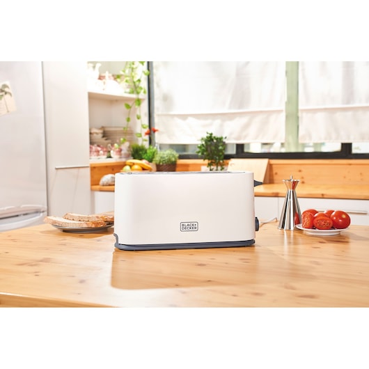 Photo of BLACKDECKER BXTO1001E white toaster on a kitchen counter with bread and tomatoes nearby.