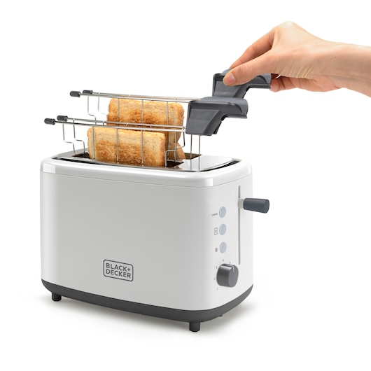 A white BLACK+DECKER toaster with two pieces of toast inside, featuring a stainless steel rack attachment being held by a hand above the toaster. The toaster has a control panel with buttons and a dial on the side.