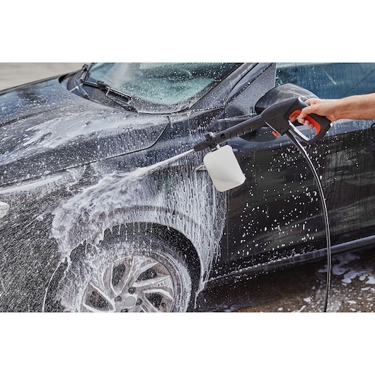 BLACKDECKER BZOSB1-LA pressure washer spraying foam on a black car during cleaning.