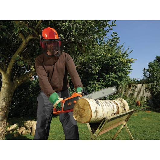 BLACKDECKER CS1835 chainsaw used outdoors to cut log on stand, person wearing safety gear.
