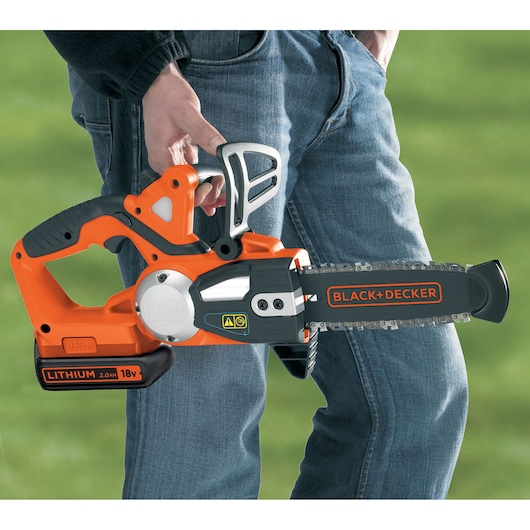 BLACK+DECKER GKC1820L20 cordless chainsaw with 18V lithium battery held by person outdoors.