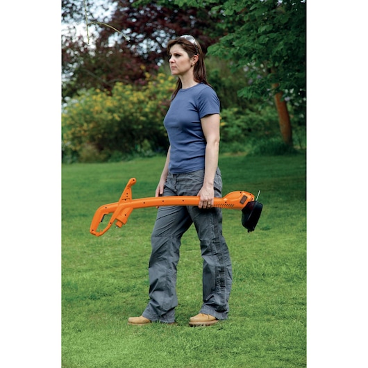 Photo of BLACKDECKER GL360 orange grass trimmer held by a person on a green lawn.