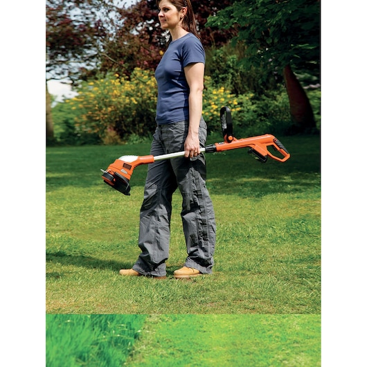 Photo of BLACKDECKER GLC1823L20 orange cordless grass trimmer carried outdoors.