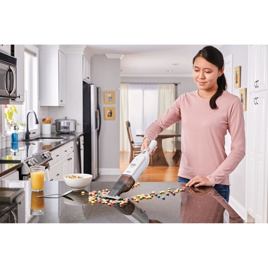 BLACKDECKER HLVC315B11 handheld vacuum cleaning spilled cereal on kitchen counter.