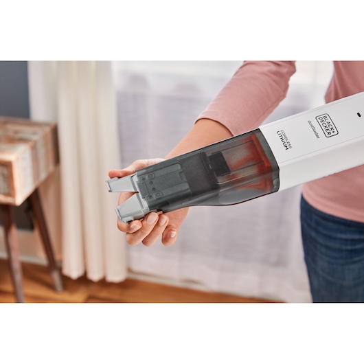 Photo of BLACK+DECKER HLVC315B11 cordless handheld vacuum being held, showing transparent dustbin and nozzle attachment.