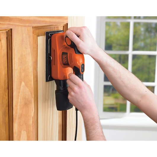 Photo of BLACKDECKER KA320E electric sander being used on a wooden door.