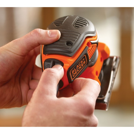 Close-up photo of BLACK+DECKER KA450 sander being held in hands, black and orange compact design.